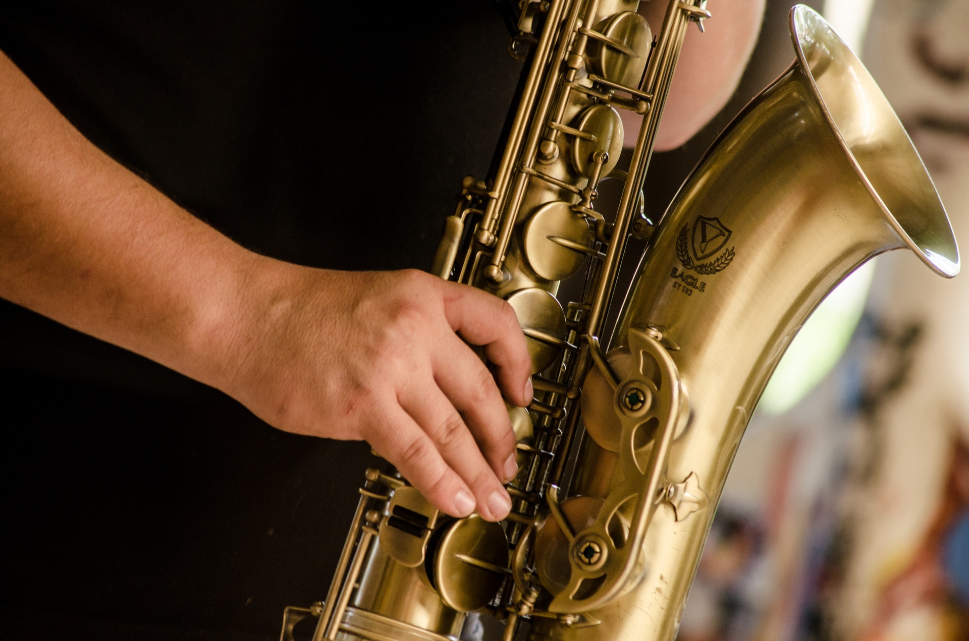Person in black shirt playing brass colored saxophone 1049690